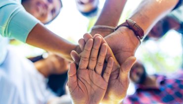Diverse of big group of peoples hands together outdoors .